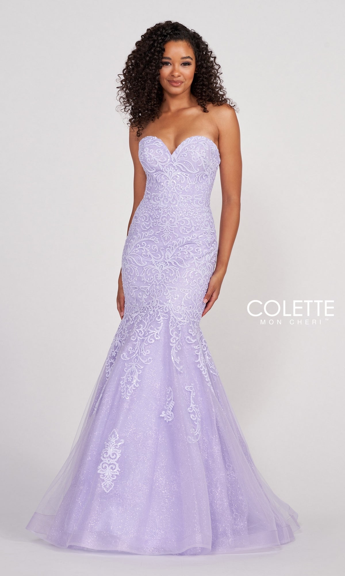 A woman stands against a plain backdrop wearing the Colette Pastel Strapless Lace Mermaid Prom Dress, featuring lace details and light purple embellishments.